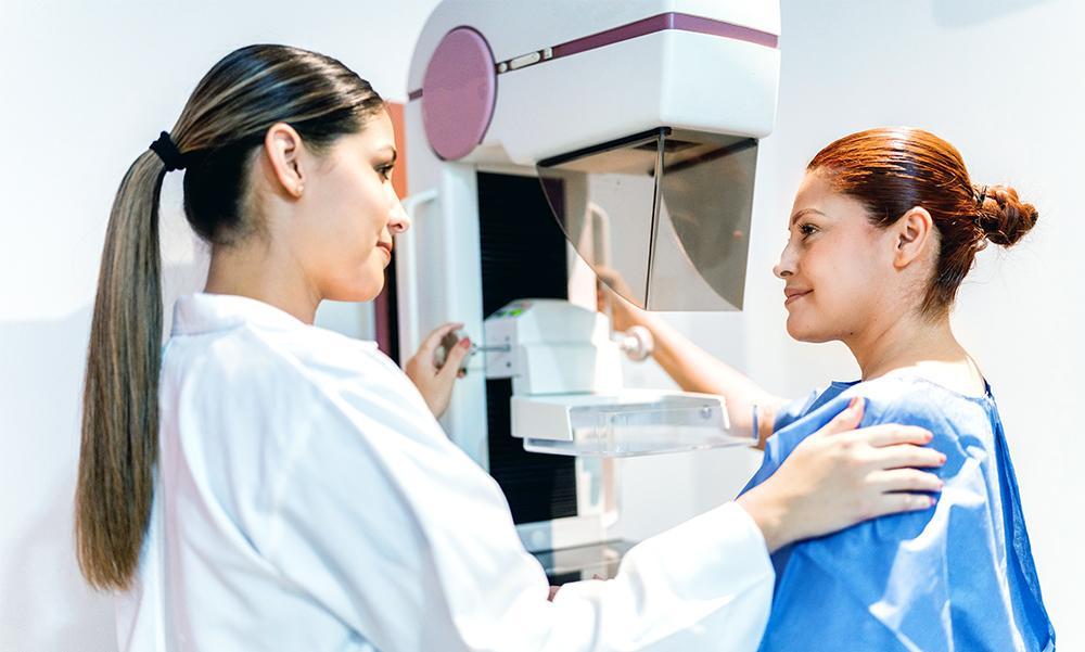 Technician and patient preparing for a mammogram.