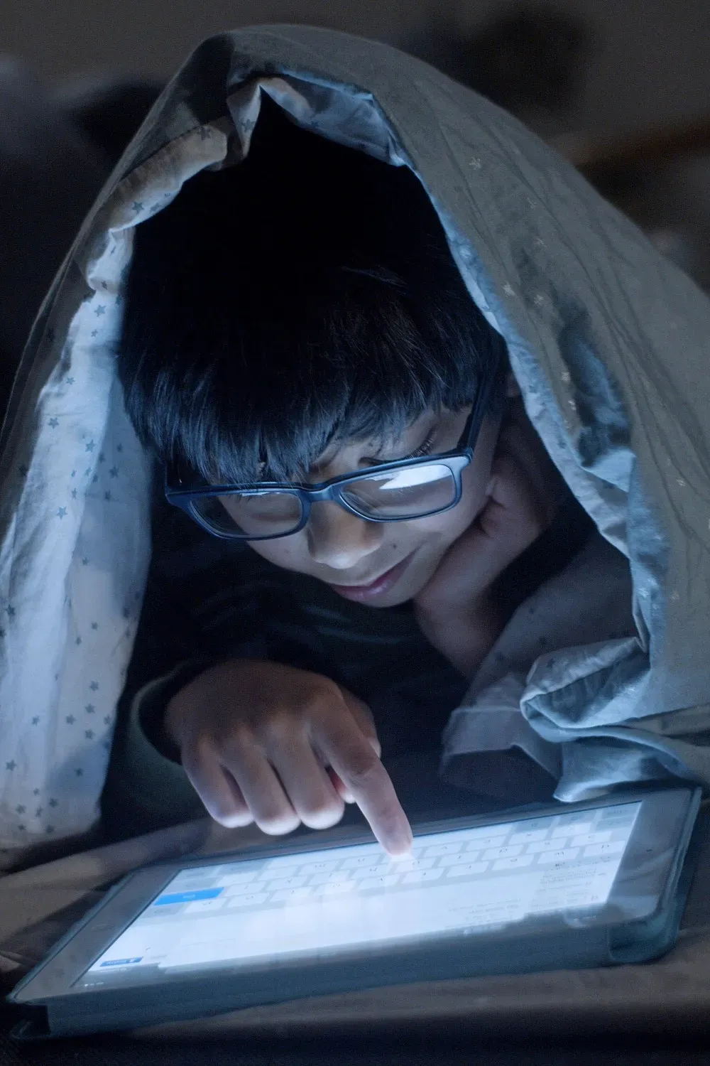 Child using a tablet in bed