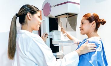 Technician and patient preparing for a mammogram.